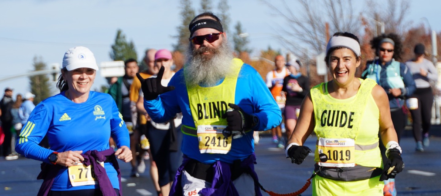 Blind man with beard running with guide in a race.