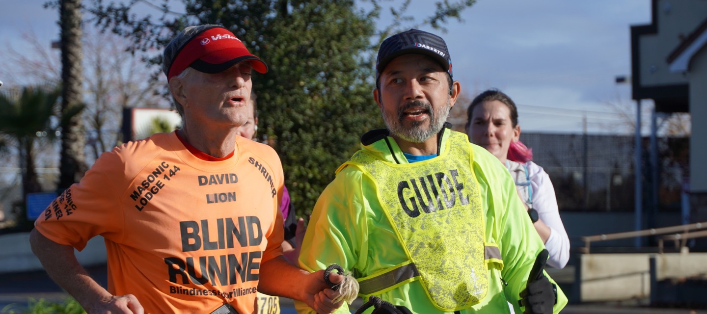 Guide and blind runner running together in race.