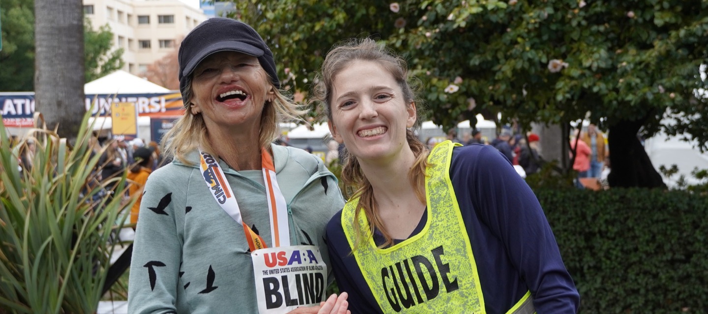 Guide and visually impaired runner posing for photo after a race