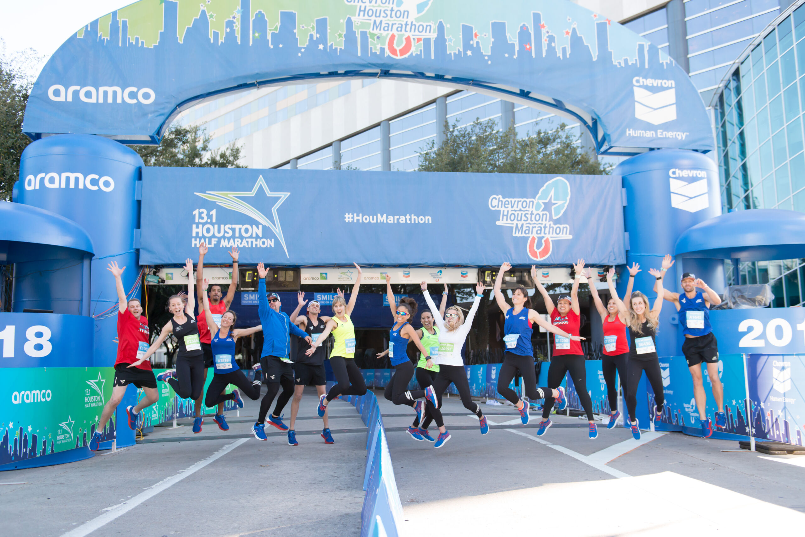 Runners jumping up at the finish line of the Houston Marathon.